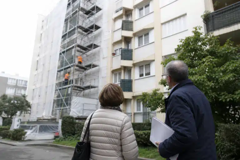 Deux personnes observant un immeuble avec échafaudage