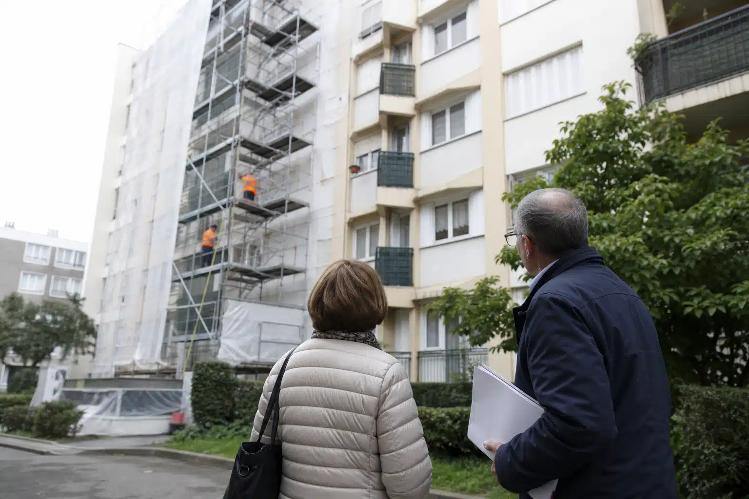 Deux personnes observant un immeuble avec échafaudage